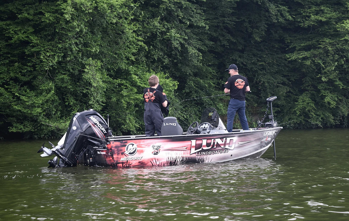 A man and a child wearing litime t-shirt fish together from a Lund professional fishing boat 
