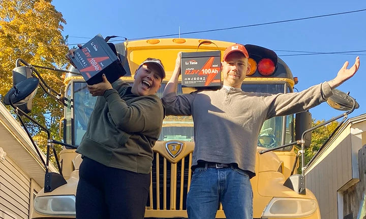 A man and woman joyfully hold a LiTime 12V 100Ah battery in front of a rv, celebrating their mobile living setup