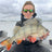 A happy angler proudly shows off a large perch she caught from her fishing boat with litime trolling motor battery